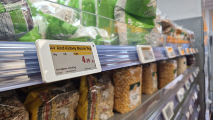 Ein digitales Albasca Synchtag Preisschild (ESL) in einer Befestigungsschiene an einem Supermarktregal.